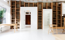 白い床に椅子とテーブルが並び壁際に木材で作られたおしゃれなデザインの棚が並んでいる